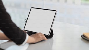 Vue rapprochée de la main d’une femme d’affaires travaillant avec une maquette de tablette numérique sur un bureau blanc dans une salle de bureau, chemin de découpage
