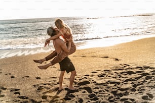 젊은 다민족 사람들이 해변에서 키스하고 함께 즐거운 시간을 보내는 아름다운 커플. 실제 사람들의 감정. 여름 서퍼 라이프 스타일 개념입니다.