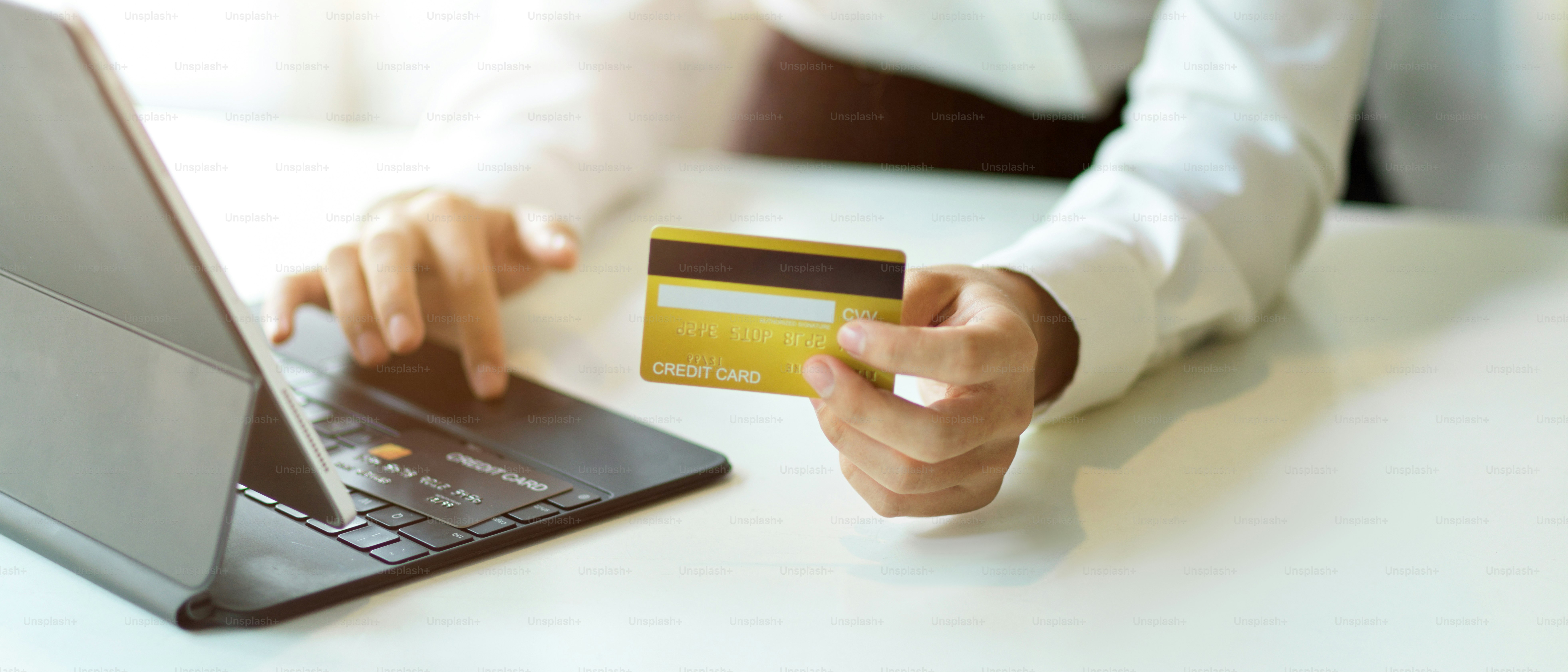 Vista ravvicinata della mano femminile che tiene la carta di credito e digita sulla tastiera del tablet per il pagamento online