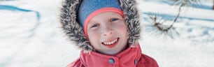 Cute adorable happy Caucasian smiling girl in pink jacket with fur hood during cold winter day. Kids outdoor seasonal activity. Funny face. Winter child portrait outside. Web banner header.