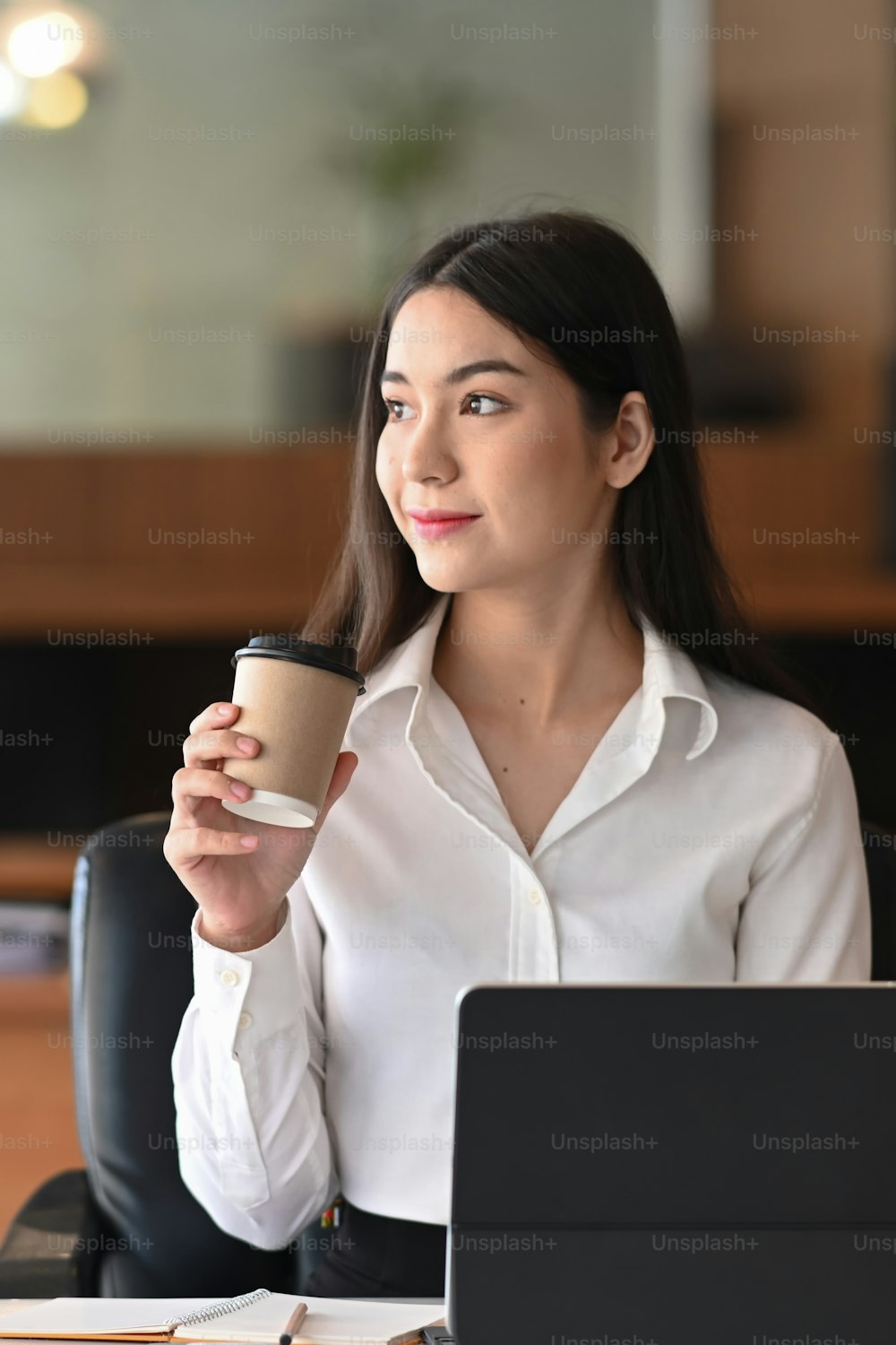 Portrait of attractive businesswoman holding coffee cup and looking away thinking of future business vision.