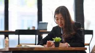 Junge Geschäftsfrau, die in einem modernen Büro arbeitet und das Smartphone benutzt.