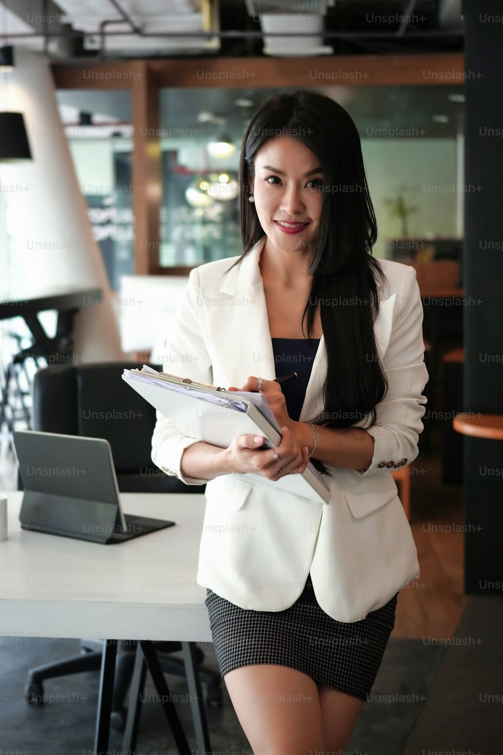 Portrait of confident businesswoman files and smiling to camera.