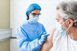 Medico o infermiera donna che somministra un'iniezione o un vaccino alla spalla di un paziente. Vaccinazione e prevenzione contro l'influenza o la pandemia virale. Concetto di vaccinazione