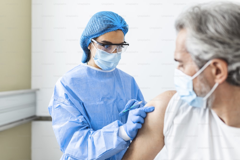 Médico ou enfermeiro do sexo feminino dando injeção ou vacina no ombro de um paciente. Vacinação e prevenção contra a gripe ou pandemia de vírus. conceito de vacinação