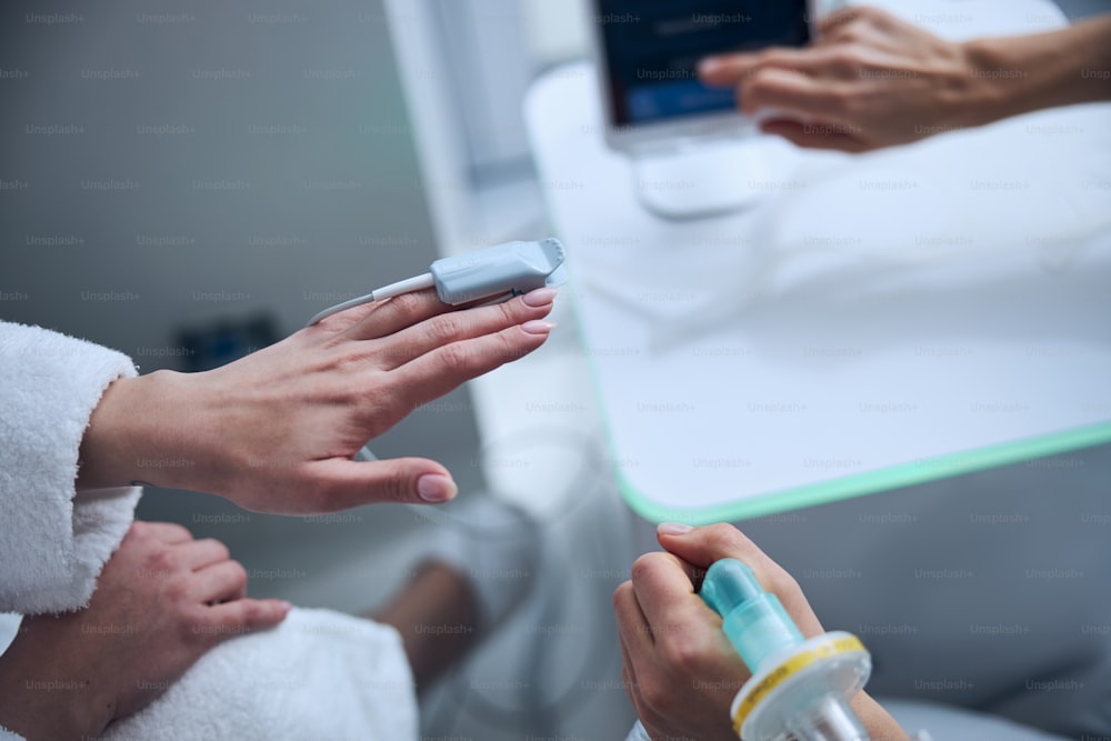 Beschnittenes Foto einer Frau mit einem Pulsoximeter auf der Fingerplatte, die sich dem Diagnosetest unterzieht