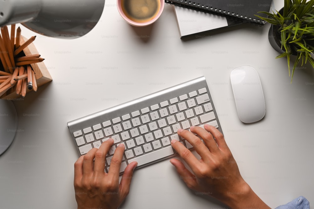 Overhead shot of businessman hands typing on wireless keyboard.