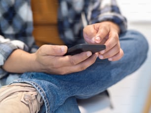 Close up view of male freelancer using smartphone in his hands while relaxed sitting at workplace