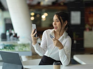 Portrait of businesswoman feeling amaze while online paying with smartphone and credit card