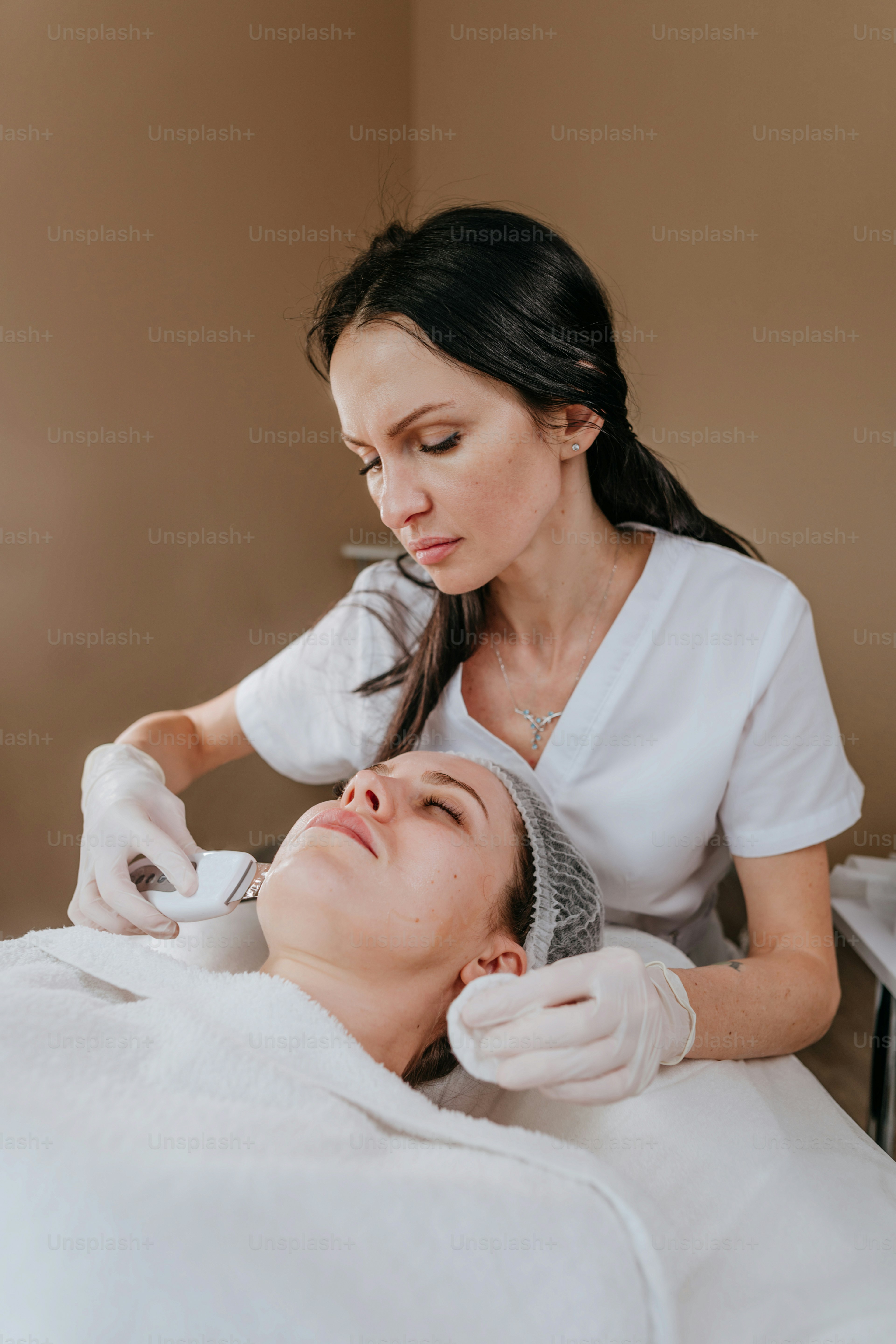 Esthetician making facial cleansing procedure using ultrasonic scin scrubber spatula in a beauty salon