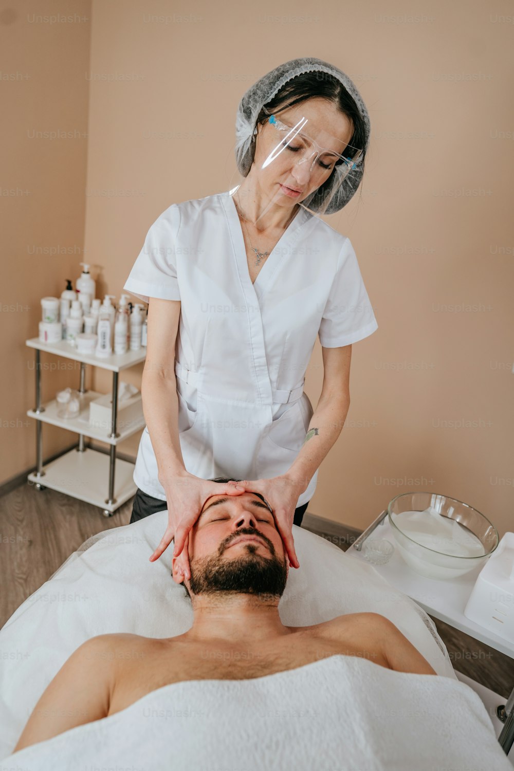 L’esthéticienne ou la facialiste donne un massage relaxant du visage à un homme