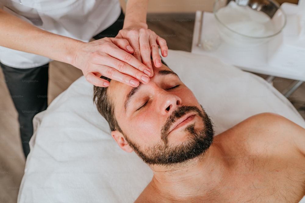 Esteticista ou facial dá uma massagem facial relaxante a um homem