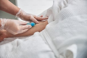 Primer plano de las manos del trabajador médico con guantes estériles sosteniendo la jeringa y haciendo la inyección en la vena de la mujer