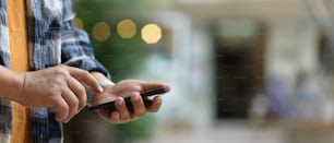 Close up view of a man touching on smartphone screen while standing in blurred background