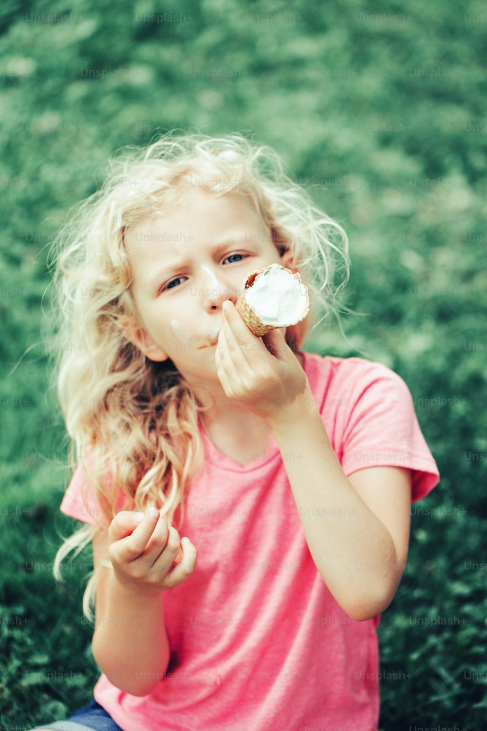 Linda chica divertida adorable con cabello largo y rubio desordenado comiendo helado lamiendo de cono de gofre. Niño comiendo sabrosa comida dulce fría de verano al aire libre. Merienda de comida congelada de verano.