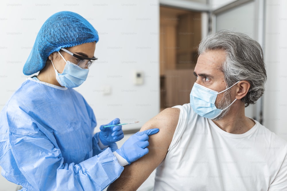 Médico vestindo terno de EPI e Máscara cirúrgica e uso de vacina com paciente infectado em sala de quarentena Covid-19 (Coronavírus) Surto de coronavírus ou Covid-19, Conceito de quarentena Covid-19
