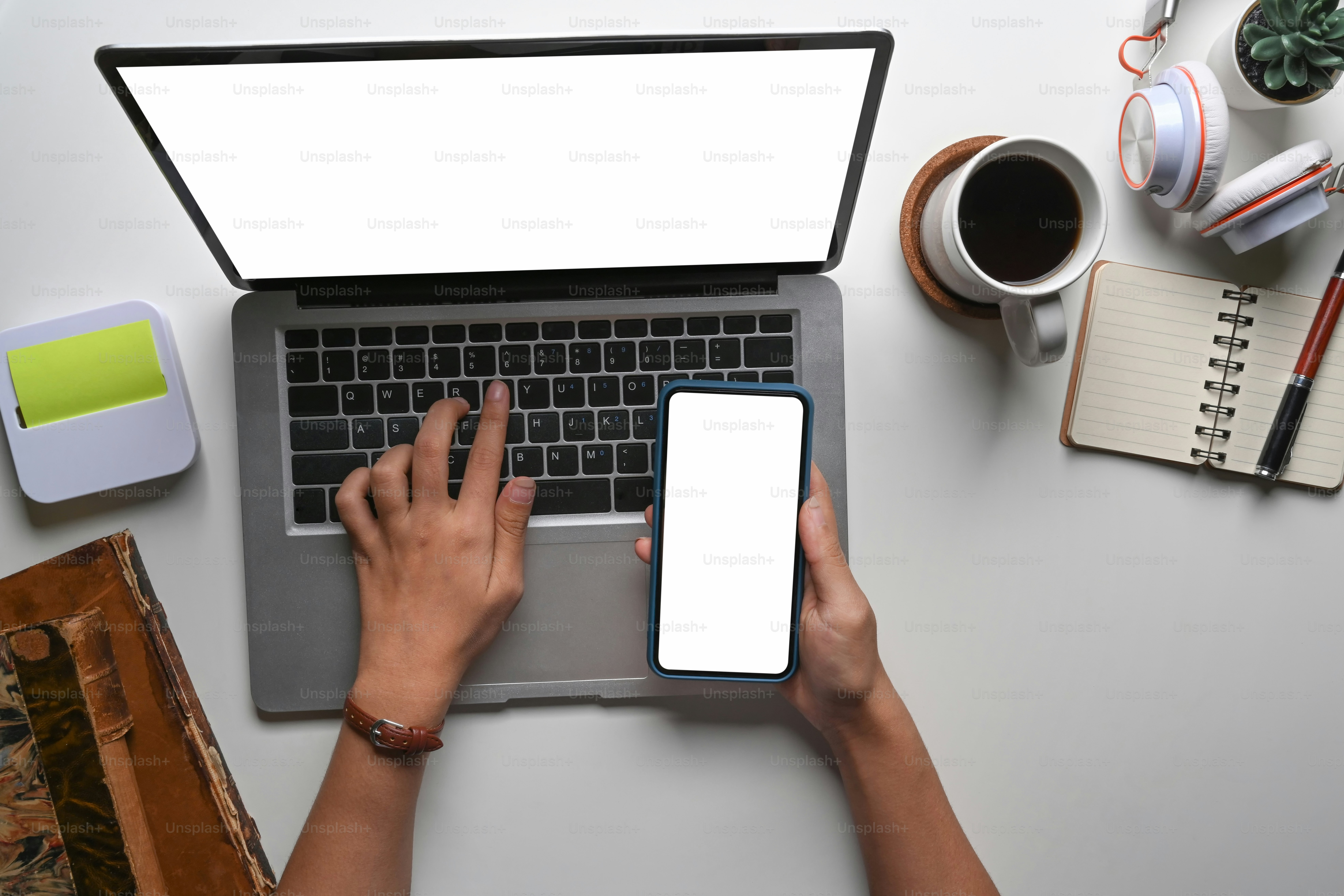 Hight view of woman hand holding mobile phone with empty screen and typing on laptop computer.