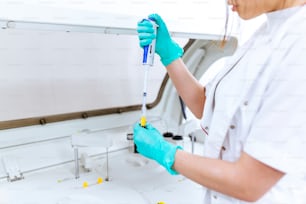 Interior of clean modern white medical or chemistry laboratory background. Laboratory scientist working at a lab with micro pipette and test tubes. Laboratory concept with woman chemist.