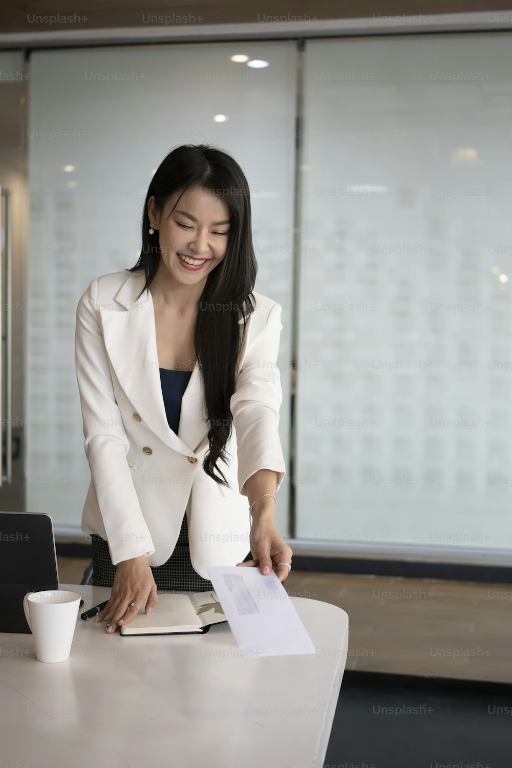 Portrait d’une femme d’affaires tenant et mettant une enveloppe en papier sur le bureau.