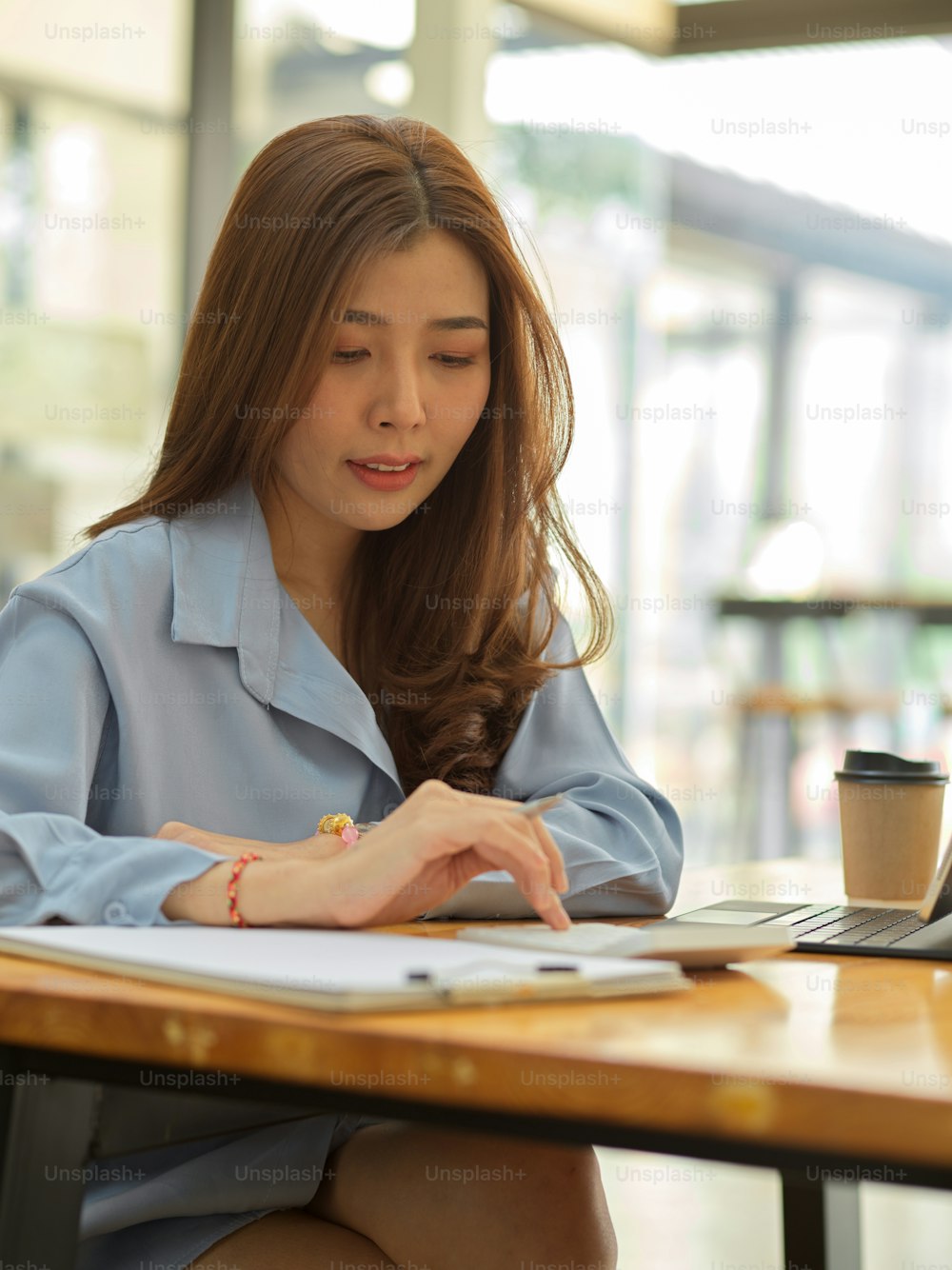 Portrait of businesswoman working with calculator and business paperwork on wooden table