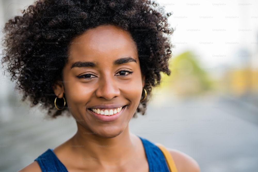 Primo piano di una donna d'affari afro che sorride mentre si trova all'aperto sulla strada. Concetto di business e urbano.