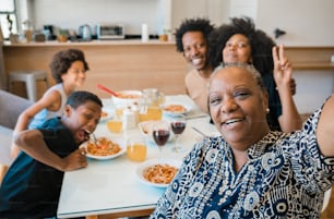 自宅で夕食をとっているときに一緒に自撮りをするアフリカ系アメリカ人の多世代家族の肖像画。家族とライフスタイルのコンセプト。