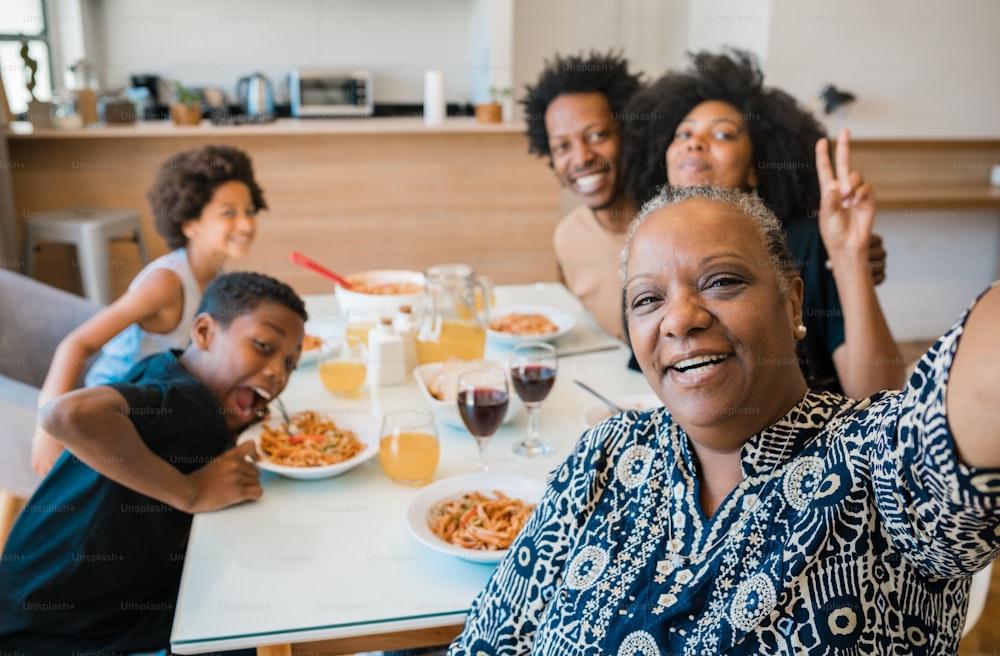 Retrato da família multigeracional afro-americana tirando uma selfie juntos enquanto jantavam em casa. Conceito de família e estilo de vida.
