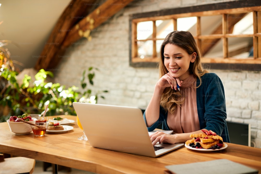 Happy female freelance worker using computer while working at home.