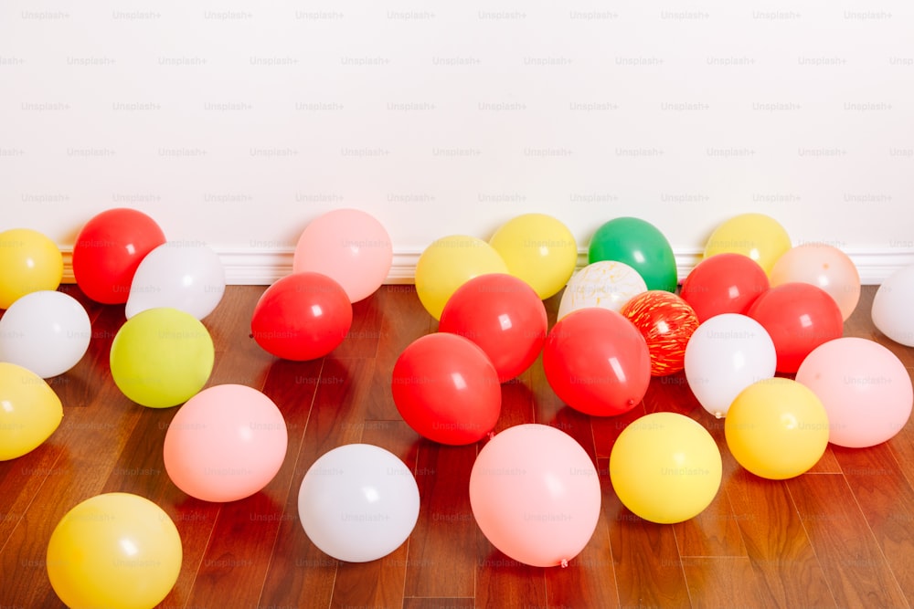 Group of many colorful air balloons lying on floor in studio apartment. Decoration interior for birthday holiday celebration. Festive background with copyspace.