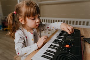 Little girl playing a synthesizer indoor
