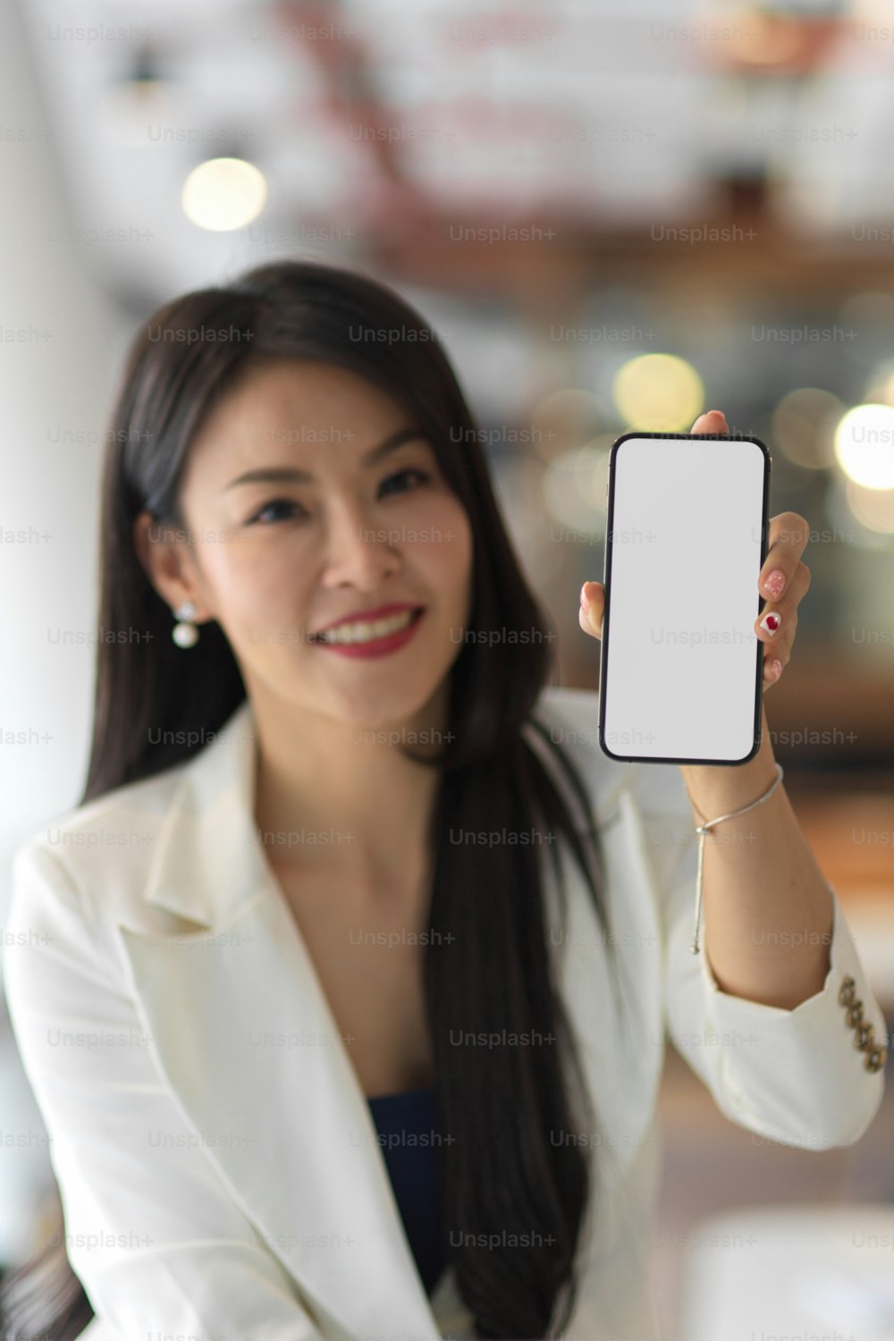 Beschnittene Aufnahme einer Geschäftsfrau, die Smartphone mit Mock-up-Bildschirm zur Kamera zeigt, Clipping-Pfad