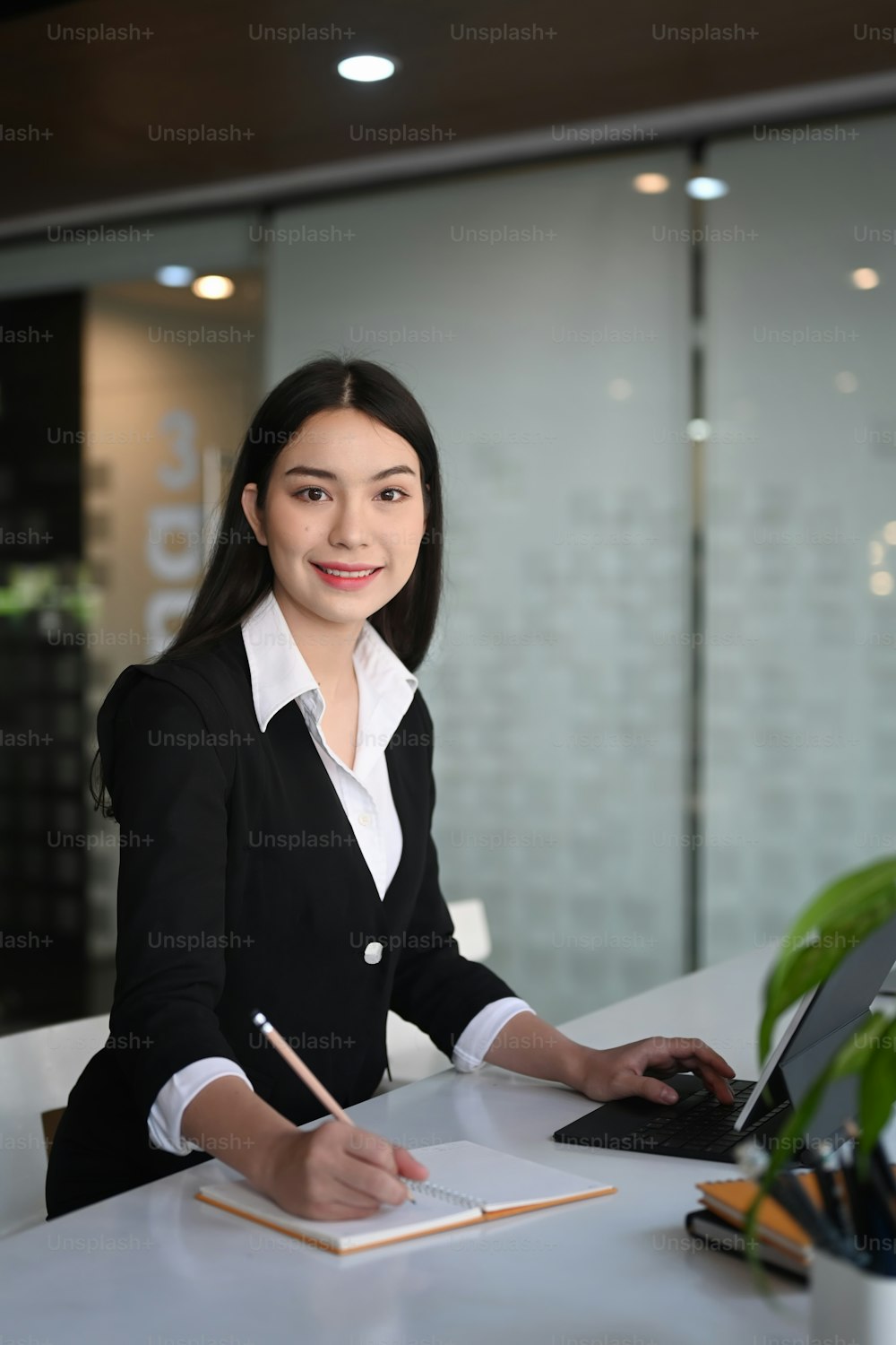 Portrait de femme d’affaires assise sur un lieu de travail moderne et souriant à la caméra.
