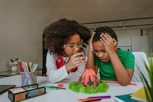 Schwester und Bruder haben Spaß daran, DIY-Vulkanmodell von Kindern zu machen, spielen Ton für das Schulprojekt. Konzept für Heimerziehung.