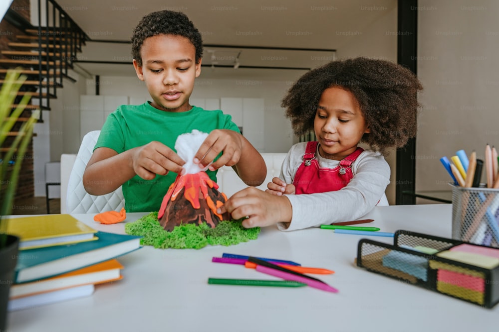 La sœur et le frère s’amusent à fabriquer un modèle de volcan bricolage à partir d’enfants qui jouent à l’argile pour le projet scolaire. Concept d’éducation à domicile.