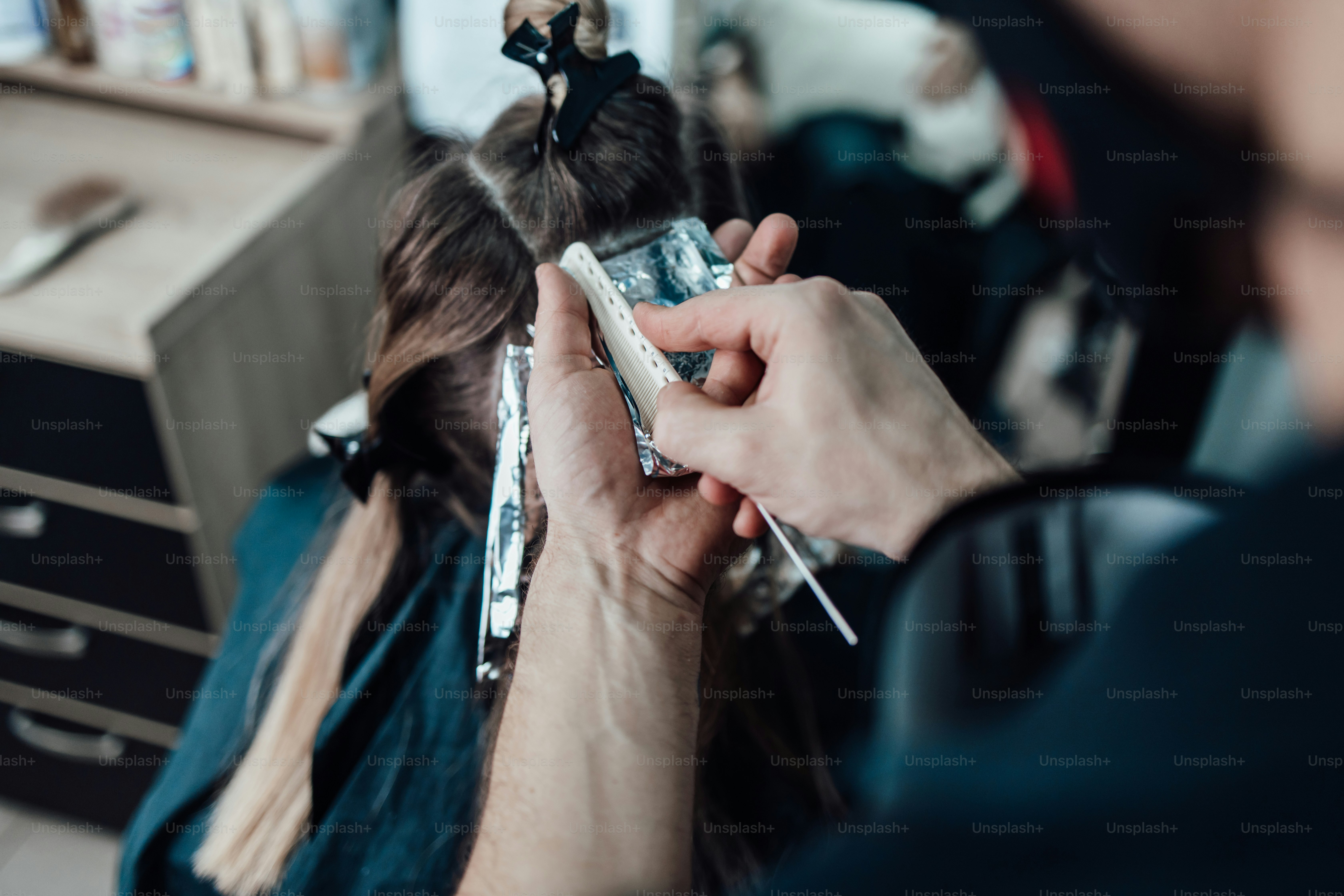 Un parrucchiere che usa un pettine per applicare riflessi di alluminio sui capelli di un cliente