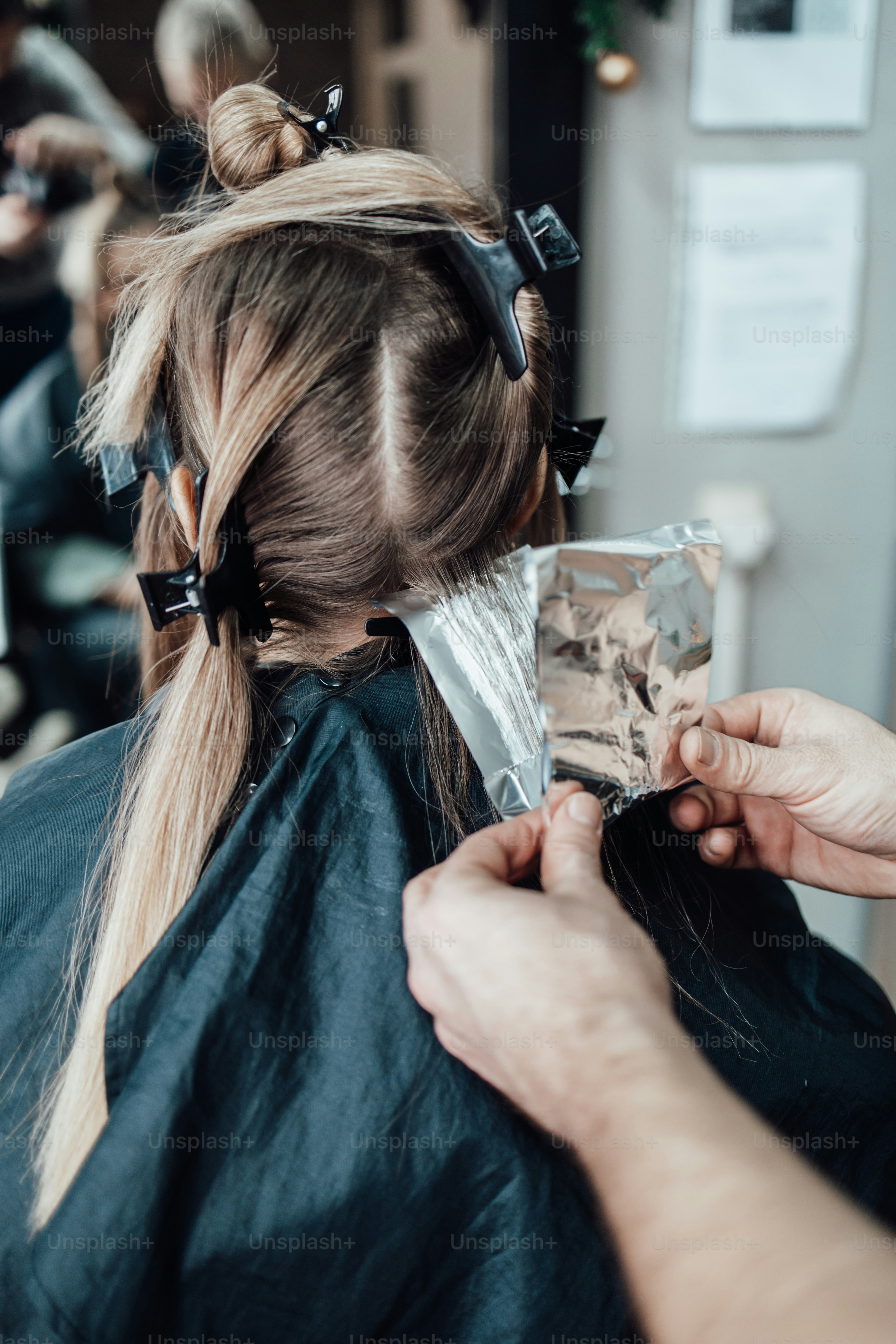 Una persona con el pelo rubio con pinzas recibiendo mechas con papel de aluminio en un salón