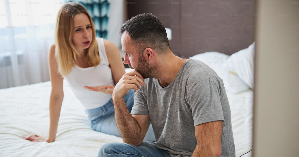 ベッドに座って夫と話しながら男が彼のあごに触れる不快なブロンドの女性の写真 – Unsplashの夫婦の画像
