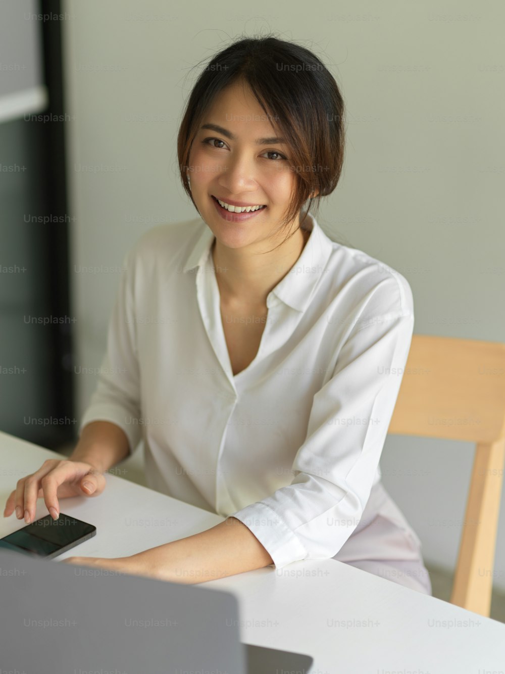 Concept de travail à domicile, portrait d’une jeune travailleuse souriant à la caméra tout en étant assise à l’espace de travail dans le salon