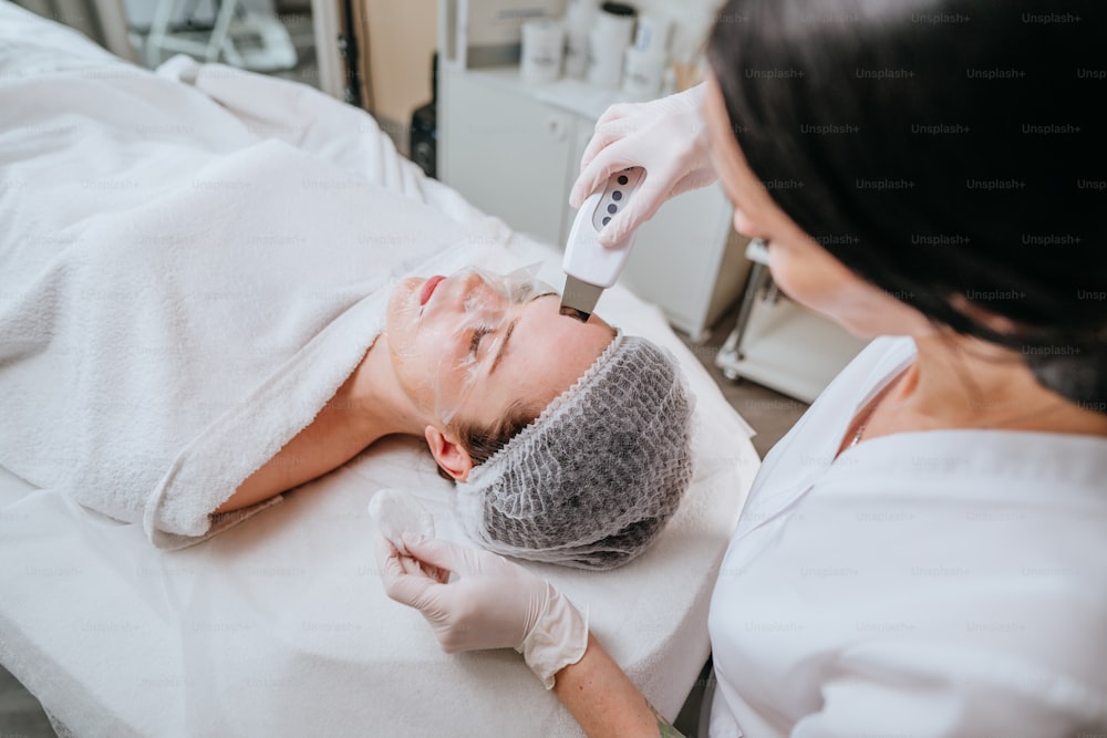 Esthetician making facial cleansing procedure using ultrasonic scin scrubber spatula in a beauty salon