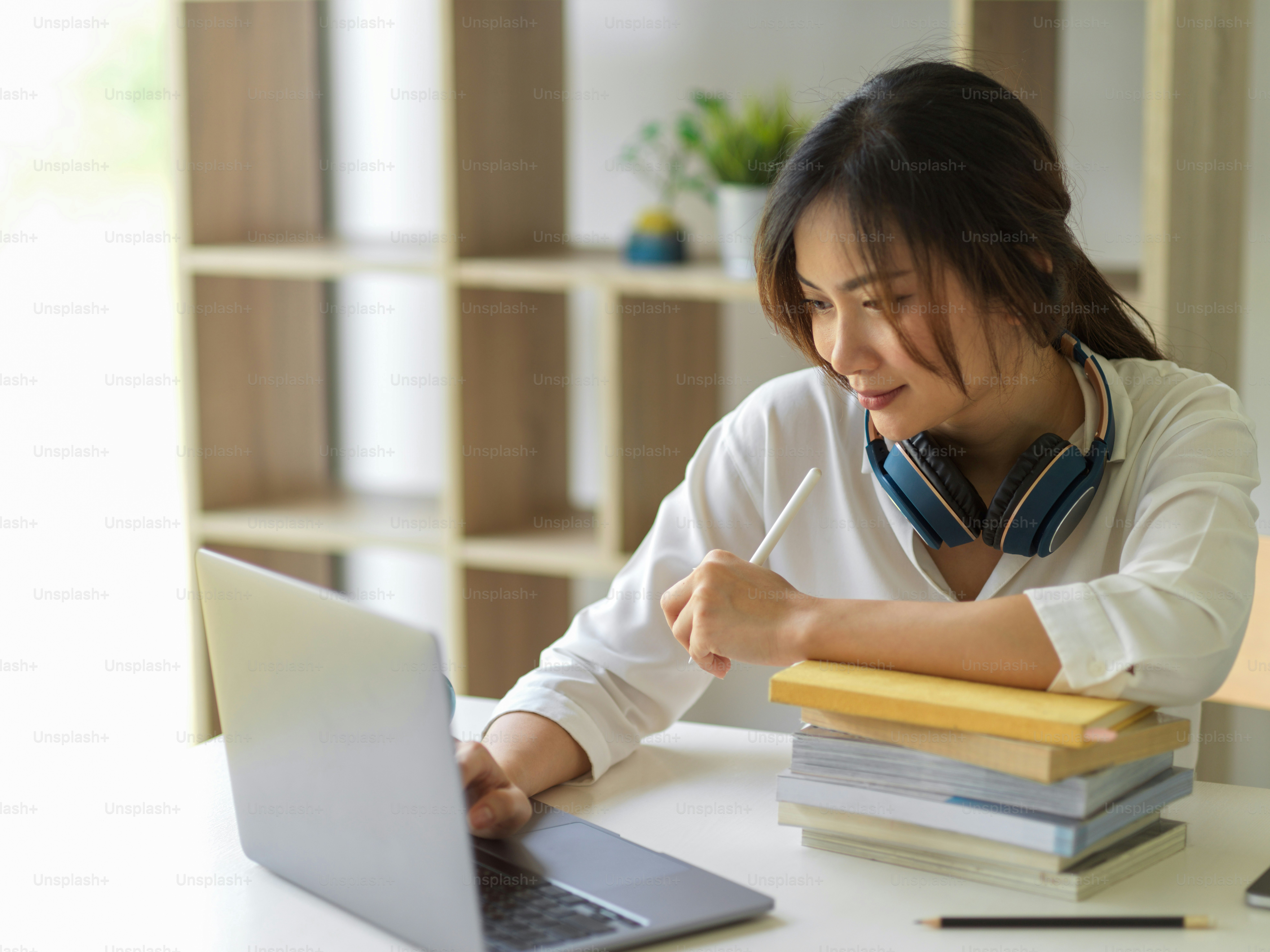 Potret mahasiswi universitas online belajar dengan laptop dan buku di ruang tamu di rumah