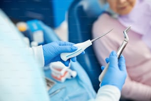 Presentación de fórceps de extracción dental y elevador dental sostenidos por un trabajador médico cerca del paciente