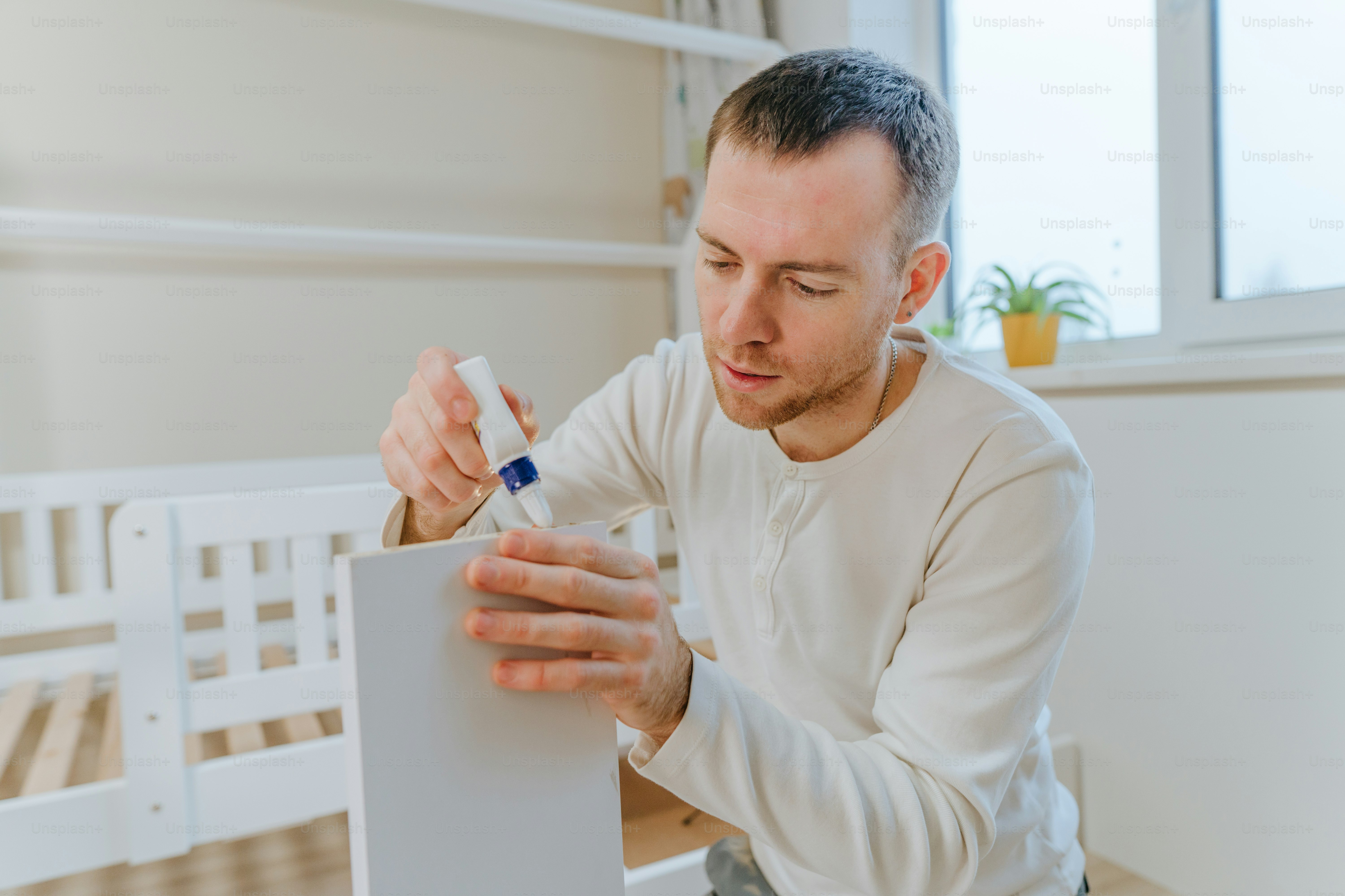Young man using glue for fixing the drawer of bed in the kids bedroom.