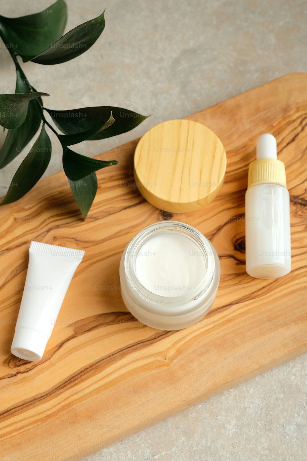 Conjunto de productos de belleza orgánicos naturales SPA y hojas verdes sobre tabla de madera. Tubo de plástico blanco de cosméticos blancos, frasco de crema corporal, suero. Diseño de packaging, branding.