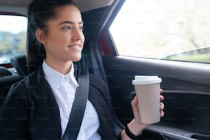 차에서 일하는 길에 커피를 마시는 비즈니스 여성의 초상화. 사업 개념입니다.