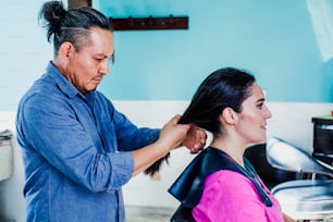 미용사로 일하고 멕시코 시티의 미용실 중소기업에서 여성 고객의 머리를 자르는 라틴 남자