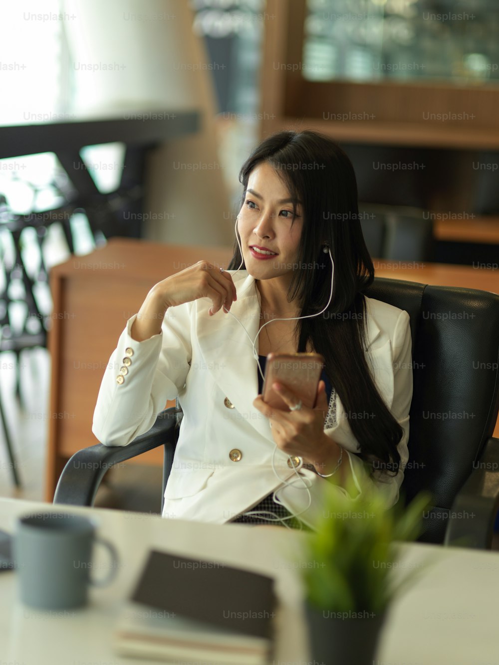 Portrait of businesswoman takes short time-out in office work using earphone and smartphone to relax