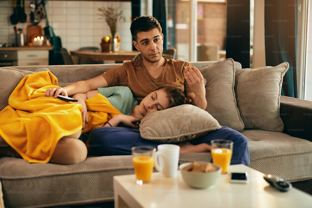 남자친구가 집에서 TV를 보는 동안 낮잠을 자는 젊은 여성.