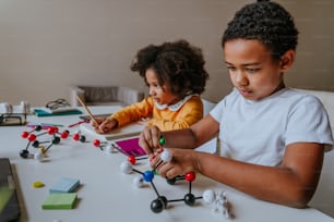Garçon et fille fabriquant un modèle moléculaire pour la science de la chimie à la maison.