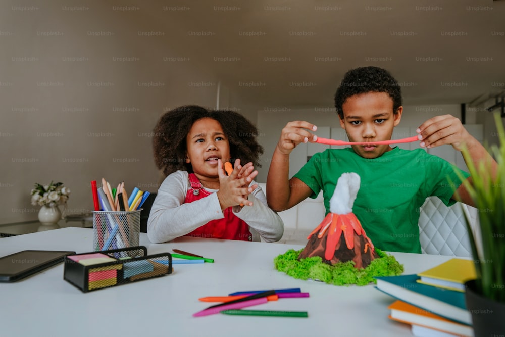 La sœur et le frère s’amusent à fabriquer un modèle de volcan bricolage à partir d’enfants qui jouent à l’argile pour le projet scolaire. Concept d’éducation à domicile.