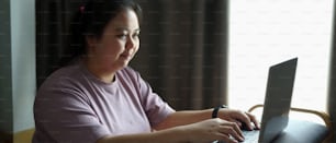 Happy obese woman working on laptop computer at home.